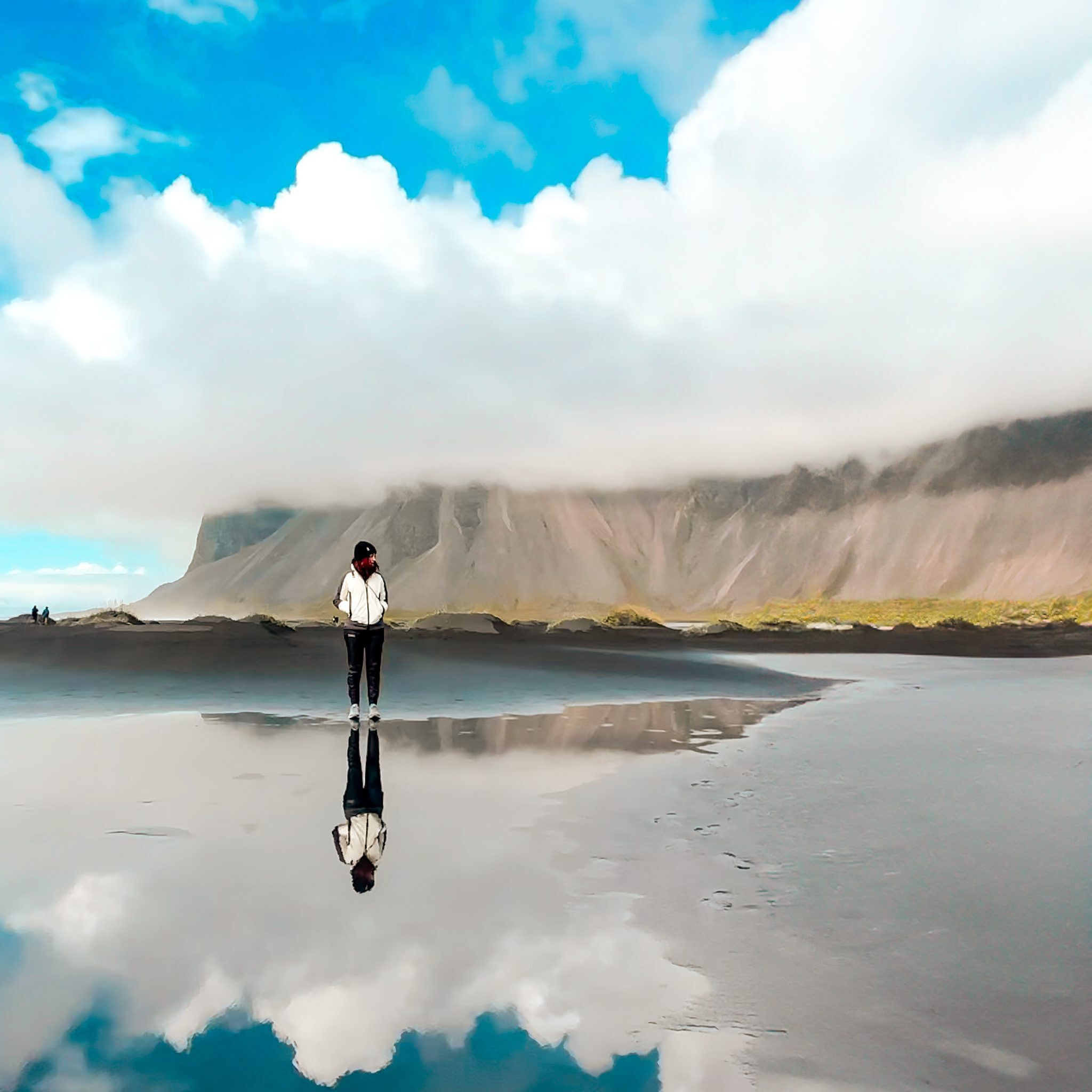 Islanda, panorama con montagne e nuvole nello sfondo, Flavia rifelssa sull'acqua.