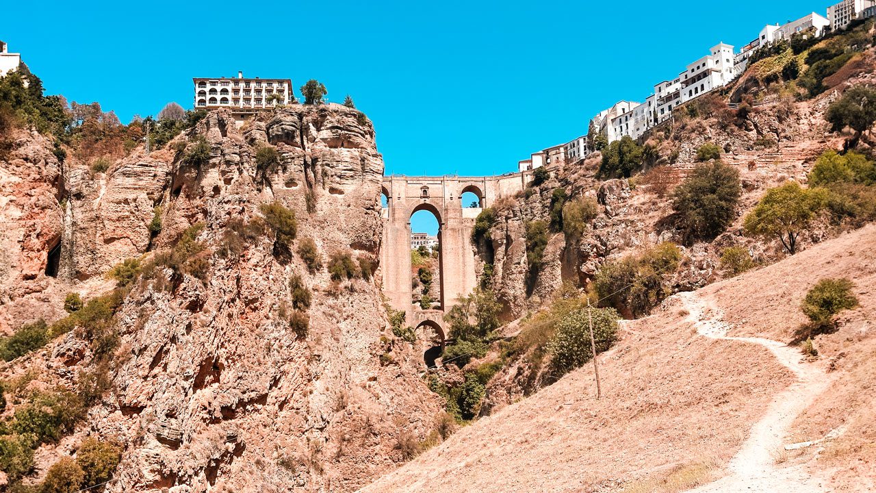 UnViaggioPerDue: Puente Nuevo di Ronda, con edifici bianchi arroccati lungo i bordi della scogliera sotto un cielo azzurro e limpido.