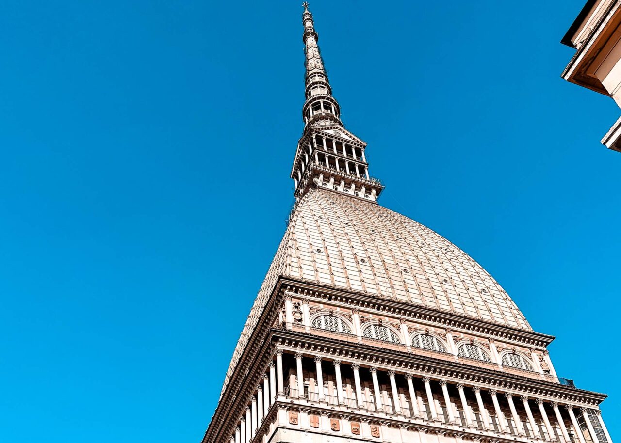 UnViaggioPerDue: La magnifica Mole Antonelliana di Torino, una grande struttura appuntita con intricati dettagli architettonici, che si staglia contro un cielo azzurro e limpido.